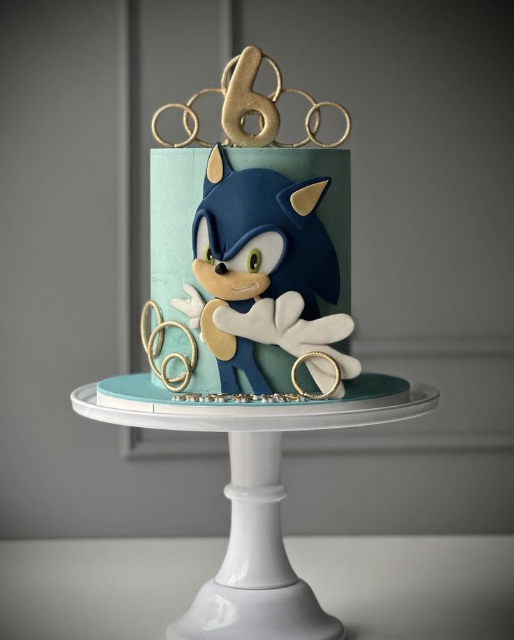 a sonic the hedgehog birthday cake on a white pedestal with blue and gold icing