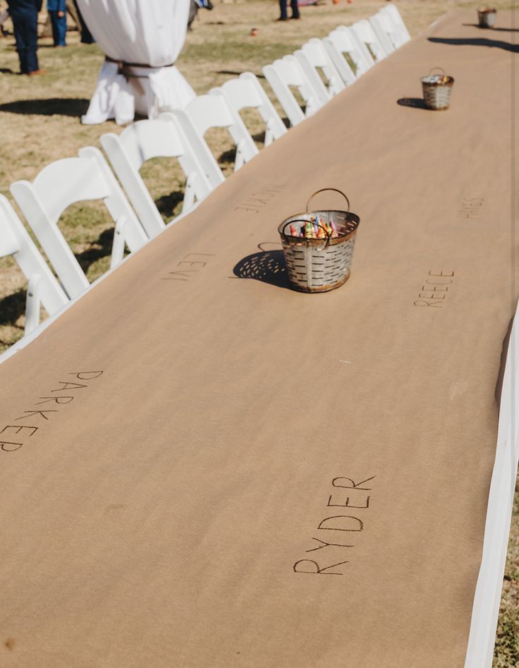 a long table covered in white chairs and a basket filled with fruit sitting on top of it