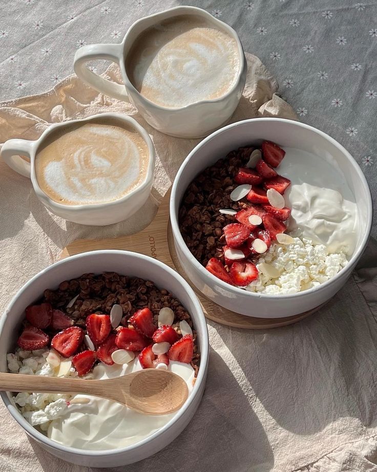 three bowls filled with cereal and strawberries on top of a table