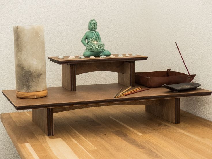 a wooden table topped with a buddha statue next to a vase on top of it