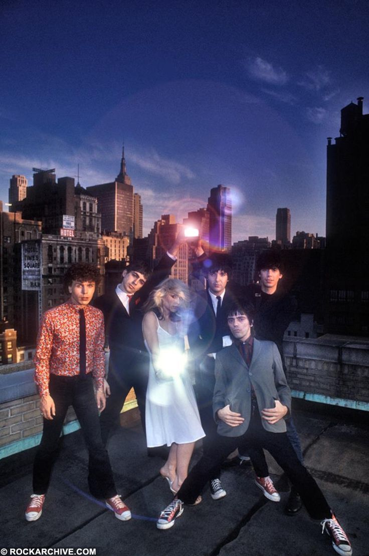 a group of people standing on top of a roof next to each other in front of a city skyline