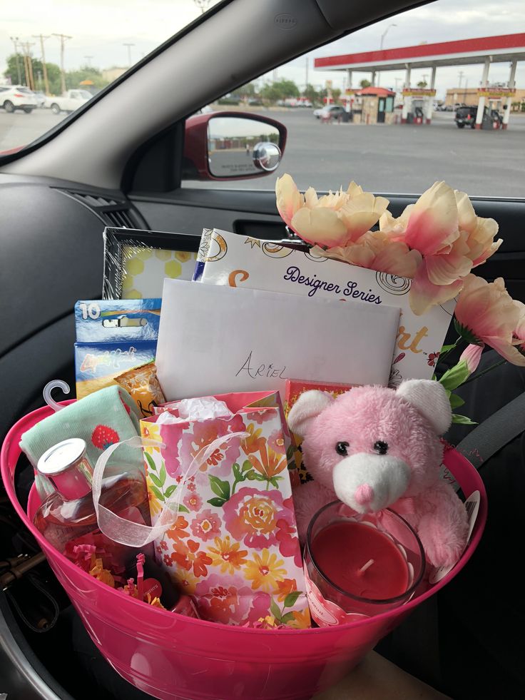 a pink basket filled with items in the back seat of a car next to a flower