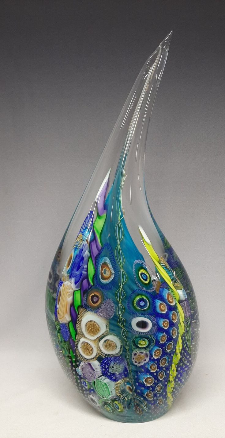 a glass vase with an artistic design on the top and bottom, sitting on a white surface