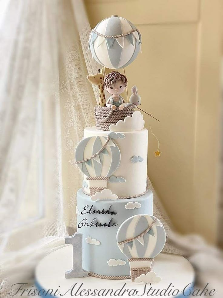 a three tiered cake with hot air balloons on it's top and the words,