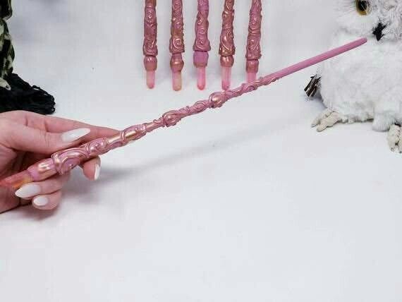 a person is holding a pink wand in front of an owl and four other objects