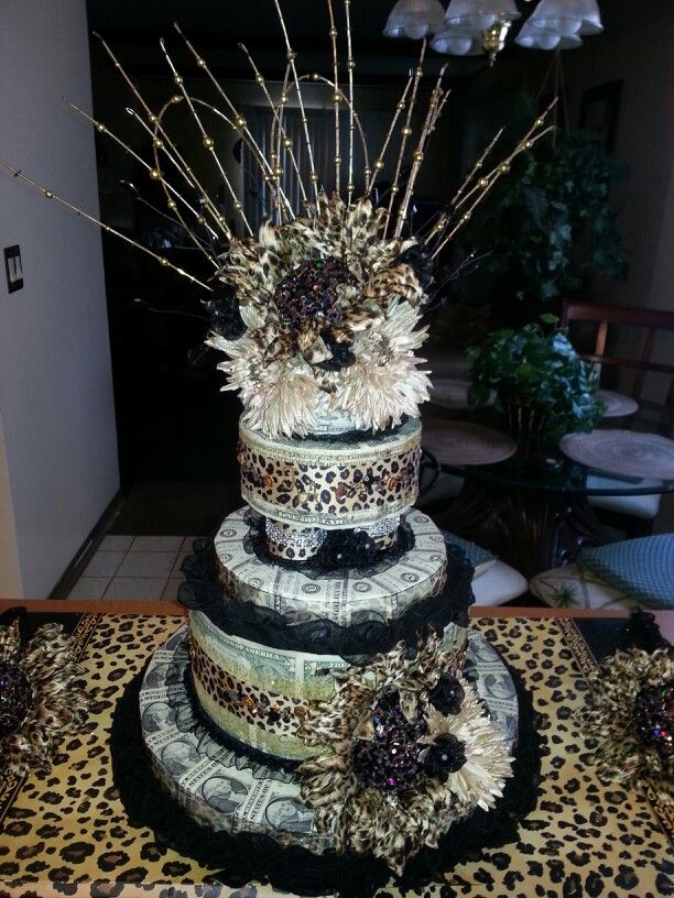 a multi tiered cake decorated with leopard print, feathers and flowers on a table