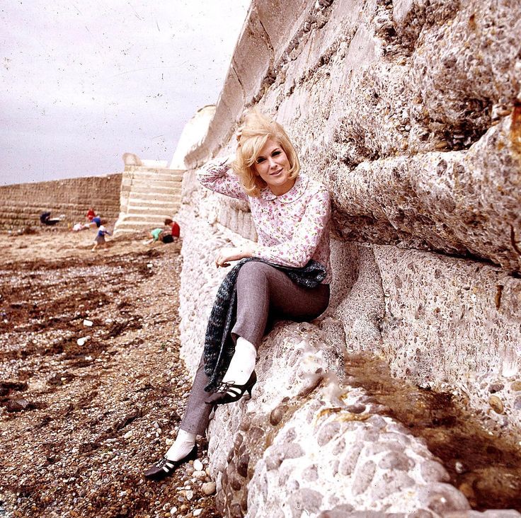 a woman sitting on the side of a stone wall