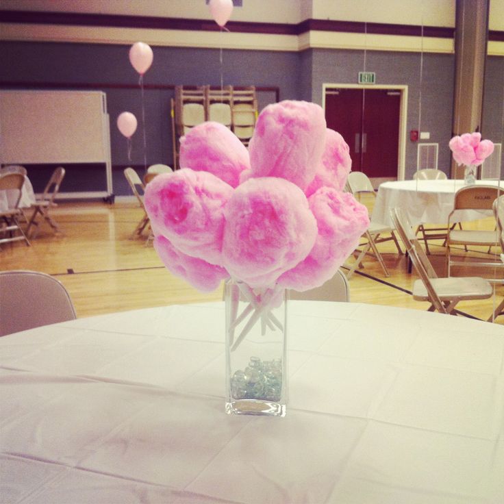 a vase filled with pink flowers sitting on top of a white tablecloth covered floor