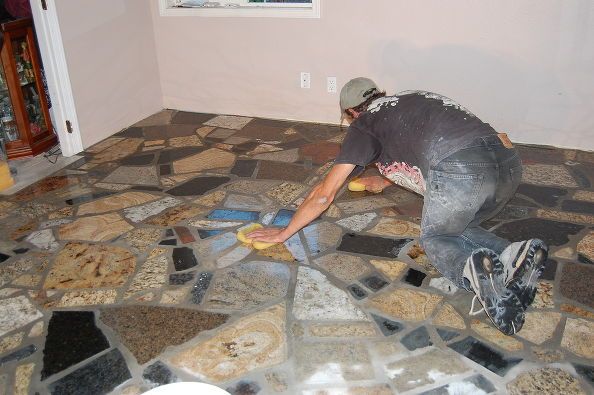 a man laying on the floor with tools in his hand and working on some tiles