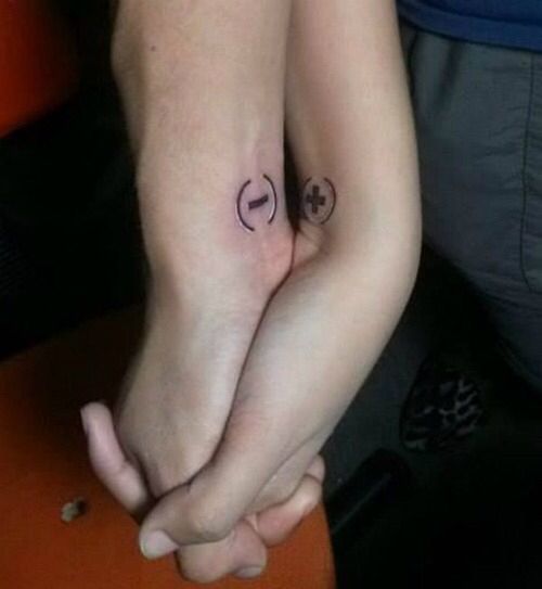 two people are holding hands with tattoos on their arms and the other one has a smiley face