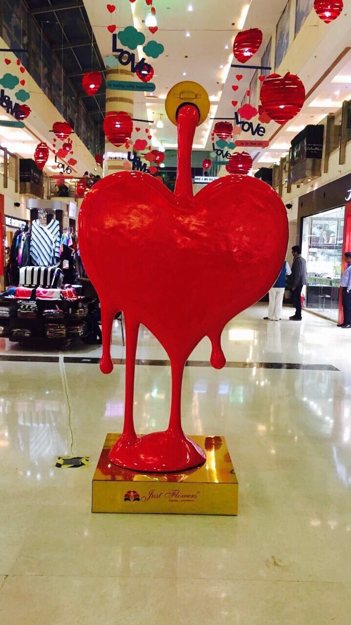 a large red heart sculpture sitting in the middle of a mall