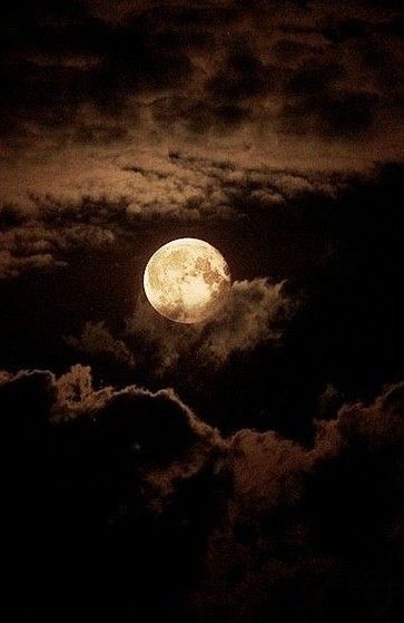 the full moon is seen through clouds at night