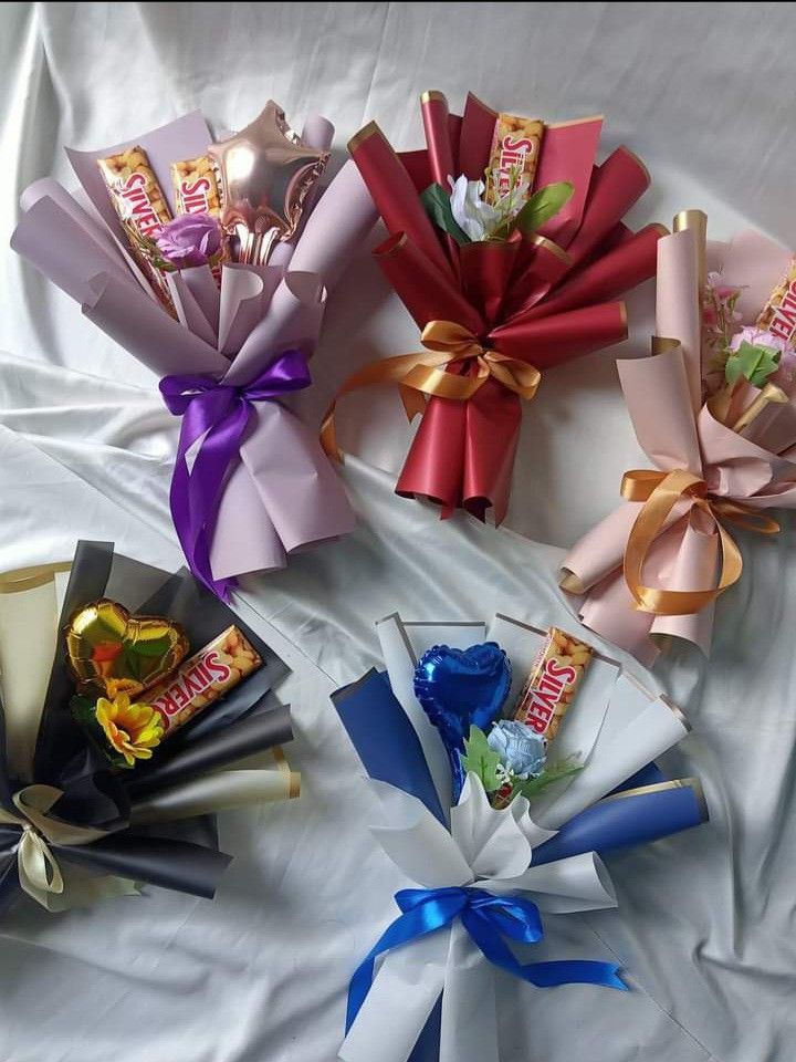 four different types of candy wrapped in satin ribbons on a white sheet with blue and gold bows