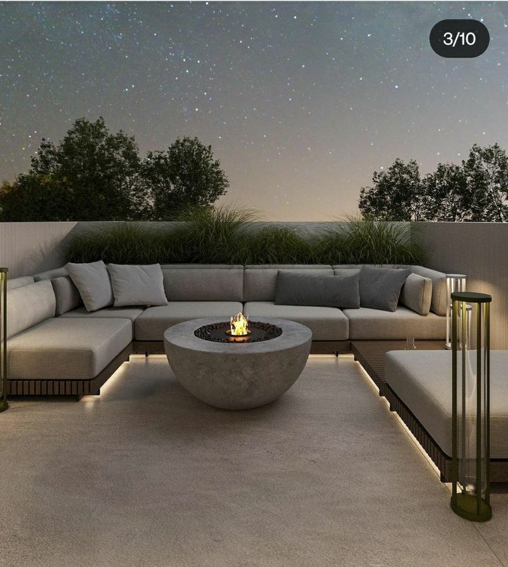 an outdoor seating area with a fire pit and stars in the night sky above it