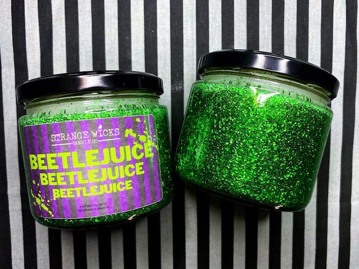 two jars with green glitter on them sitting next to each other in front of a striped wall