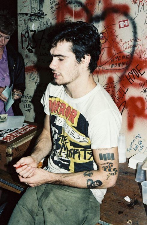 a man sitting in front of a wall covered with graffiti