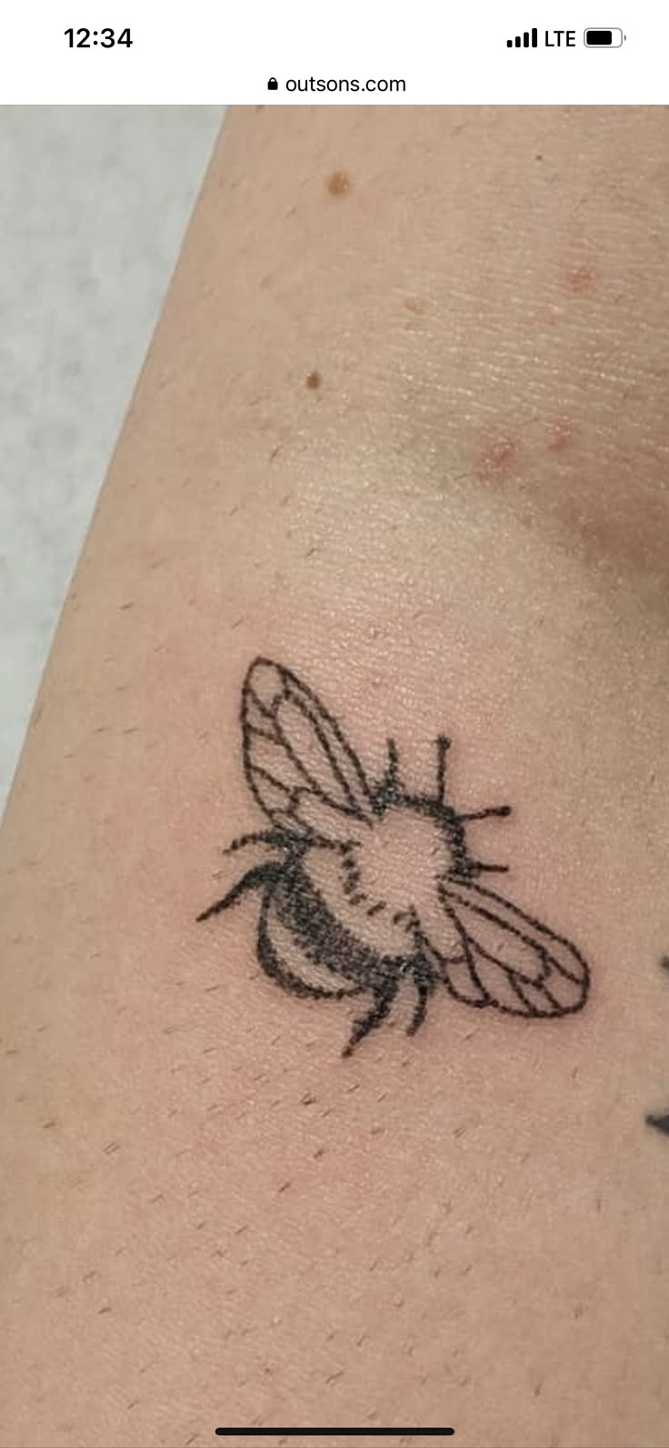 a small black and white bee tattoo on the arm