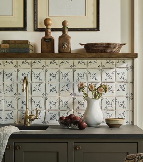 a kitchen counter with flowers in a vase and other items on the shelf above it