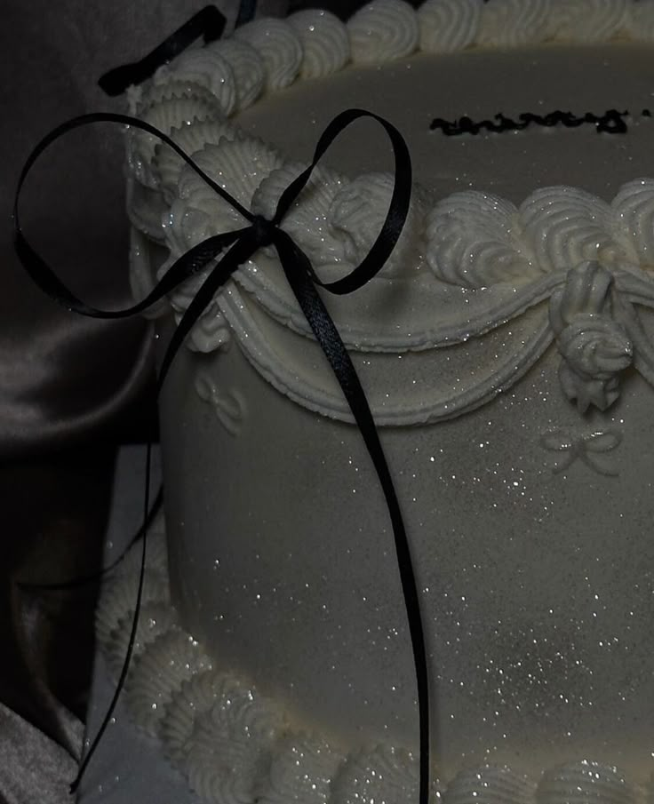 a close up of a white cake with black ribbon