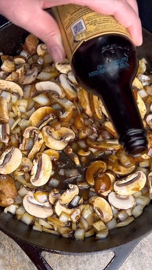 someone is pouring sauce on mushrooms in a skillet