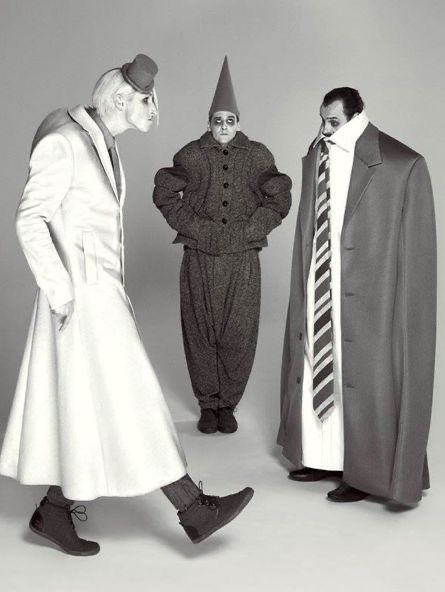 three people dressed in costumes standing next to each other and one man wearing a hat