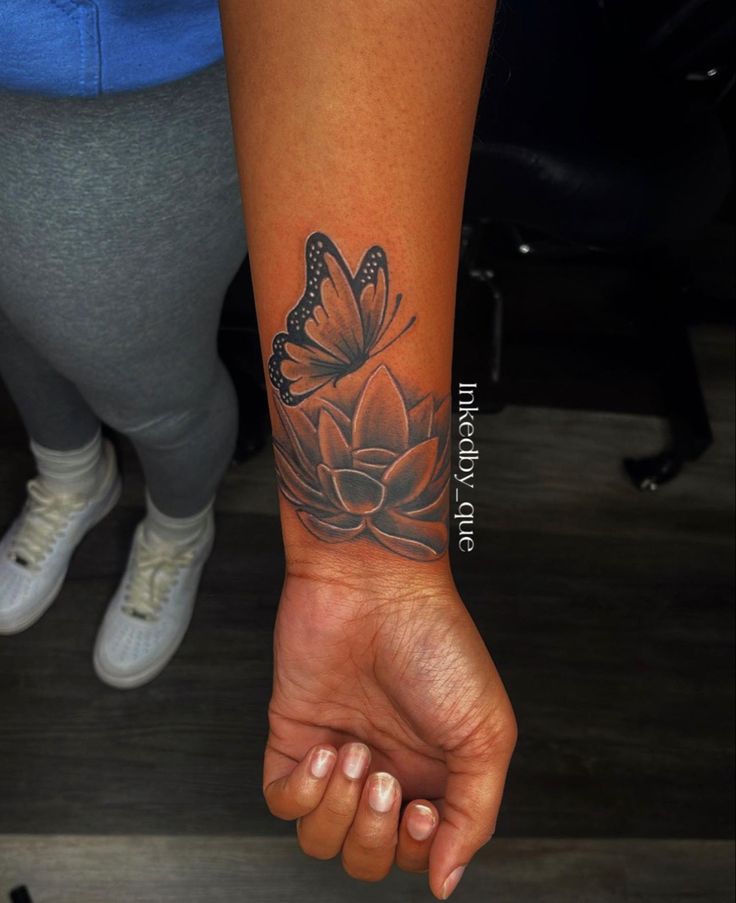 a woman's arm with a flower and butterfly tattoo on the left side of her wrist