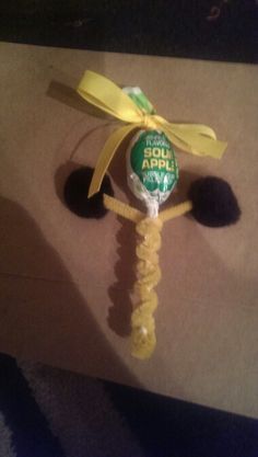 a lollipop with a yellow ribbon tied around it's head on top of a cardboard box