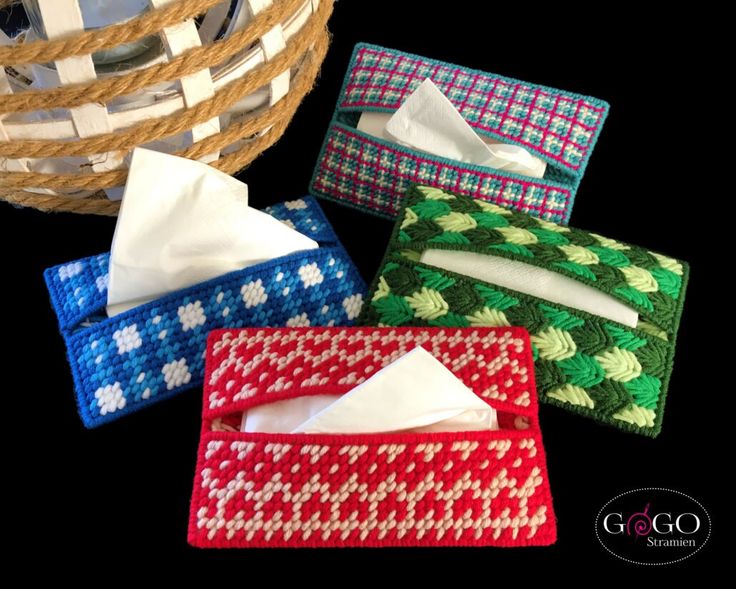 four different colored tissue boxes sitting next to each other in front of a wicker basket