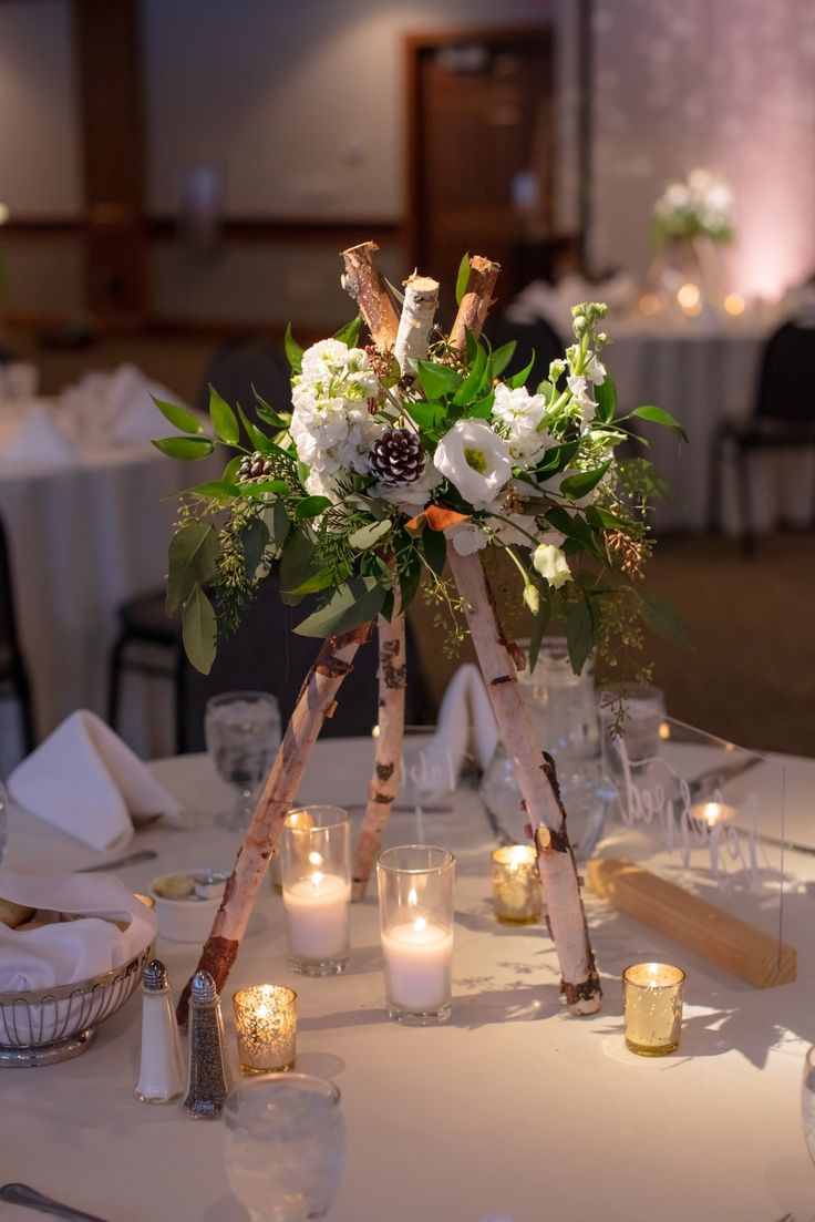 the centerpiece is decorated with white flowers and greenery, while candles are lit