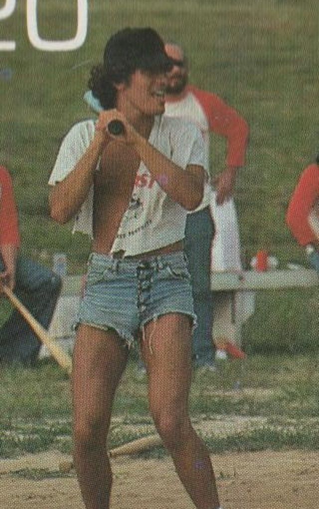 a woman holding a baseball bat on top of a field