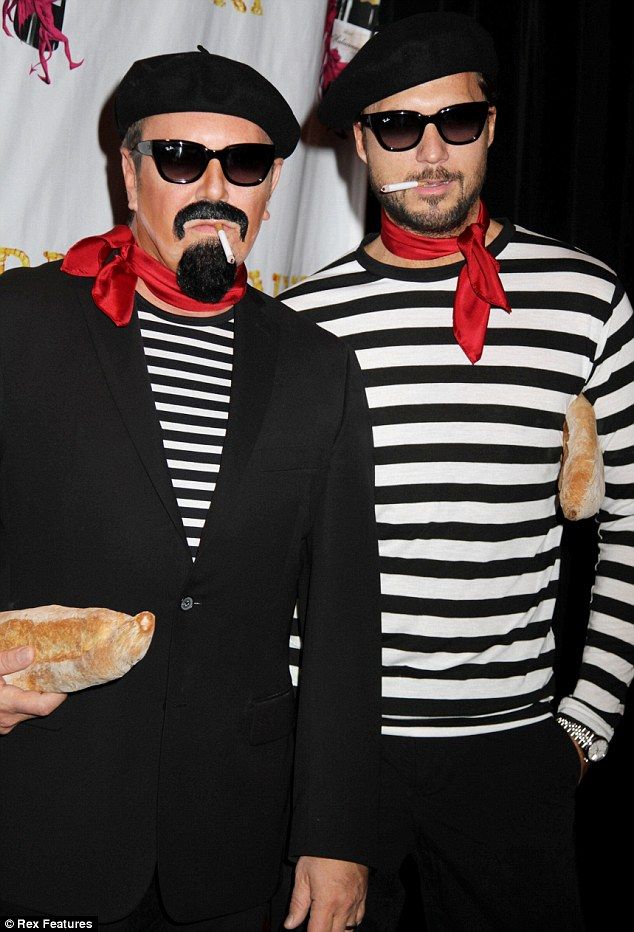 two men dressed in costumes standing next to each other and one holding a baguette