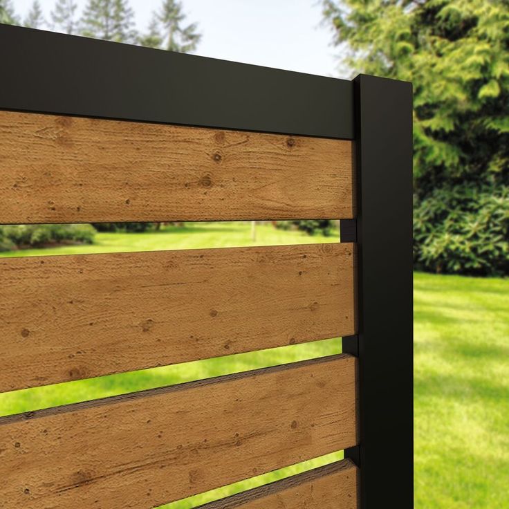 a close up of a wooden fence with grass in the back ground and trees in the background