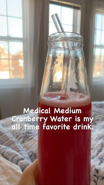 a person is holding a glass with water in it and the words medical medium cranberry water is my all time favorite drink