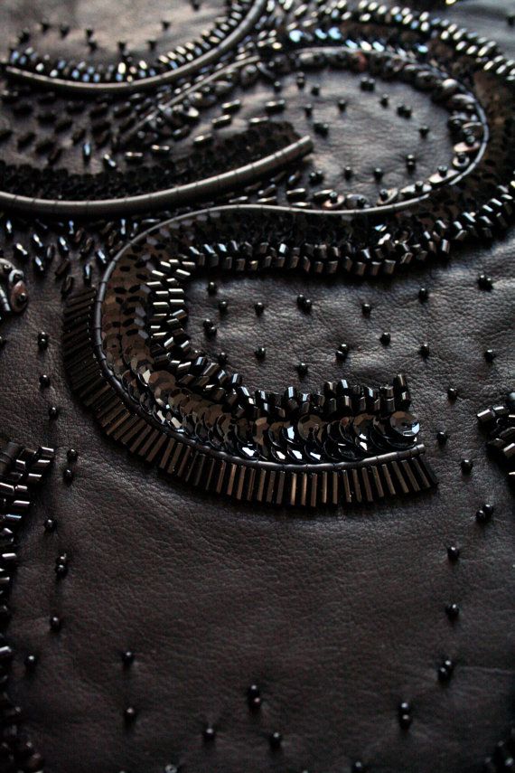 closeup of black leather with lots of beads on it and some metal pins in the middle