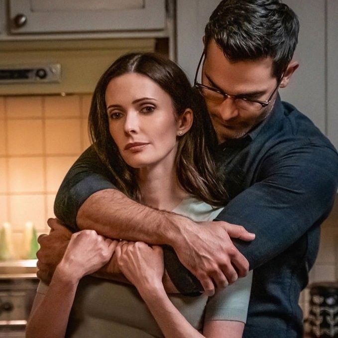 a man hugging a woman in the kitchen while she is holding her arm around him