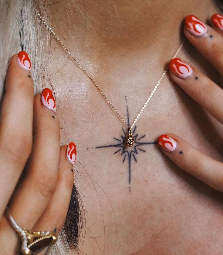 a woman with red and white nail polish on her chest holding a star shaped necklace