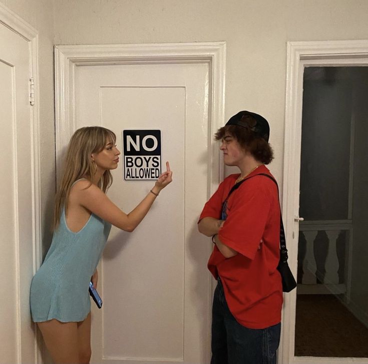 two people standing in front of a door with a no boys allowed sign on it