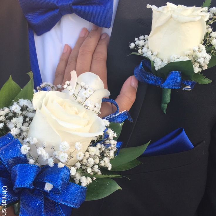 two white roses and baby's breath boutions are being held by a man in a tuxedo