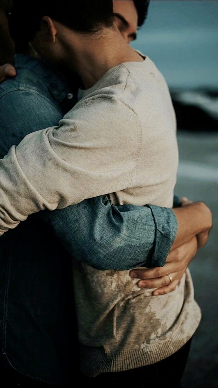 a man and woman embracing each other on the beach