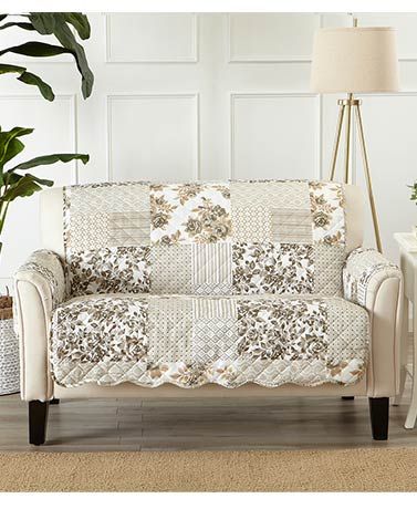 a white couch sitting next to a potted plant on top of a wooden floor