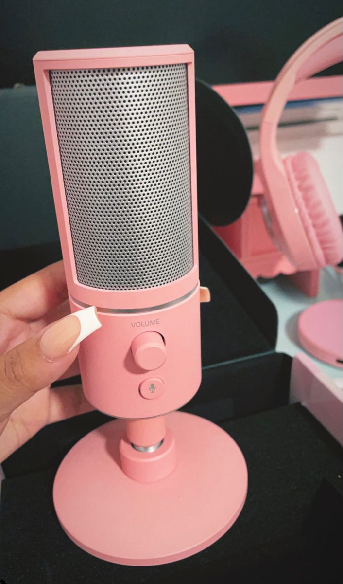 a person holding a pink microphone in front of a mirror with headphones on it