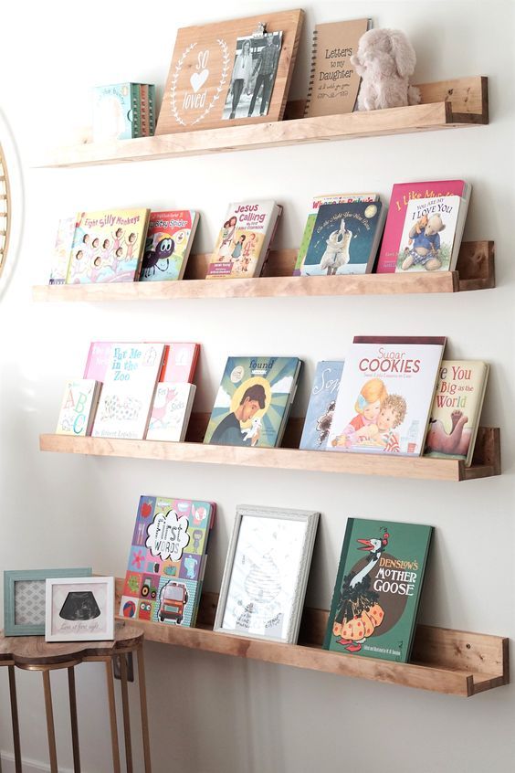 books are lined up on wooden shelves above a table