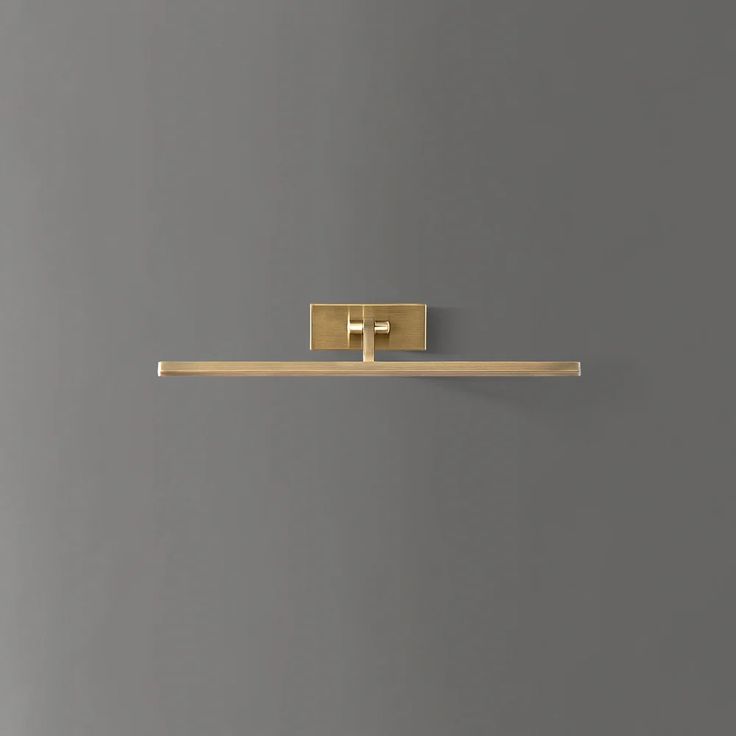 a gold toilet paper holder on a gray wall