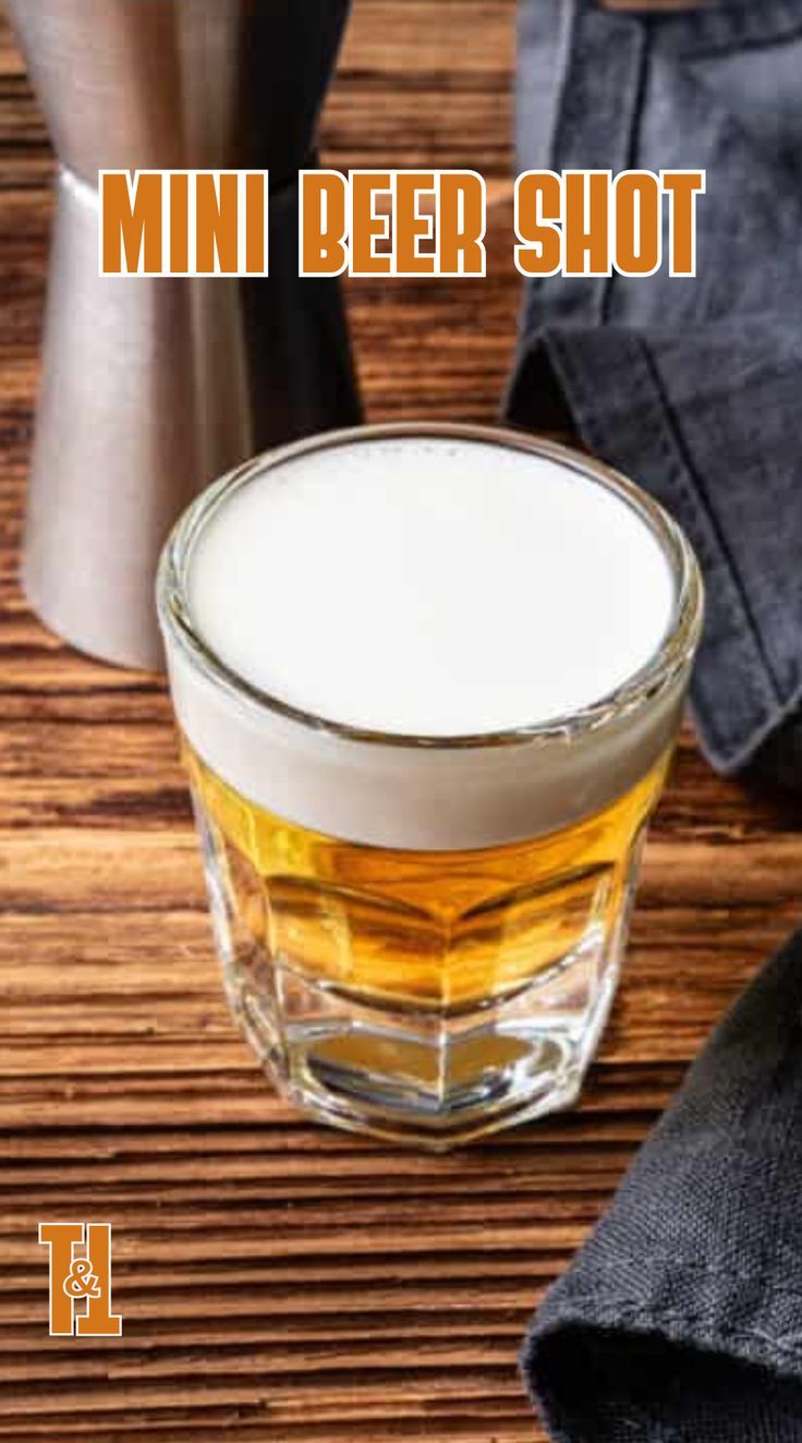 a close up of a drink in a glass on a table with the words mini beer shot