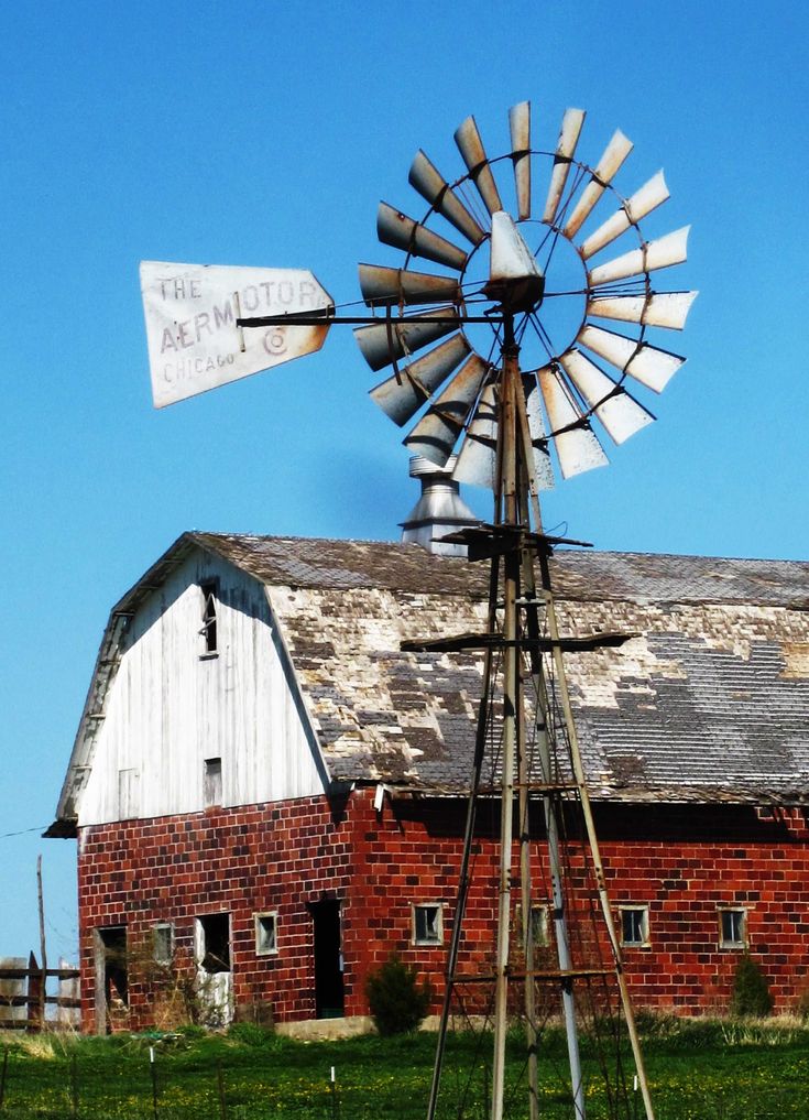 an old red brick barn with a windmill