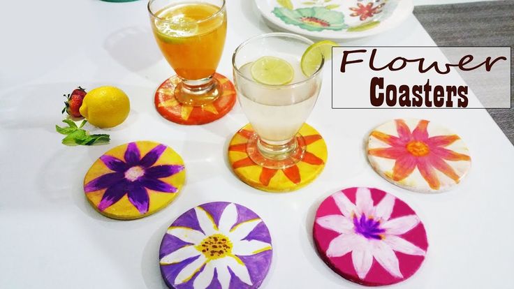 four coasters with flowers on them sitting on a table next to drinks and plates