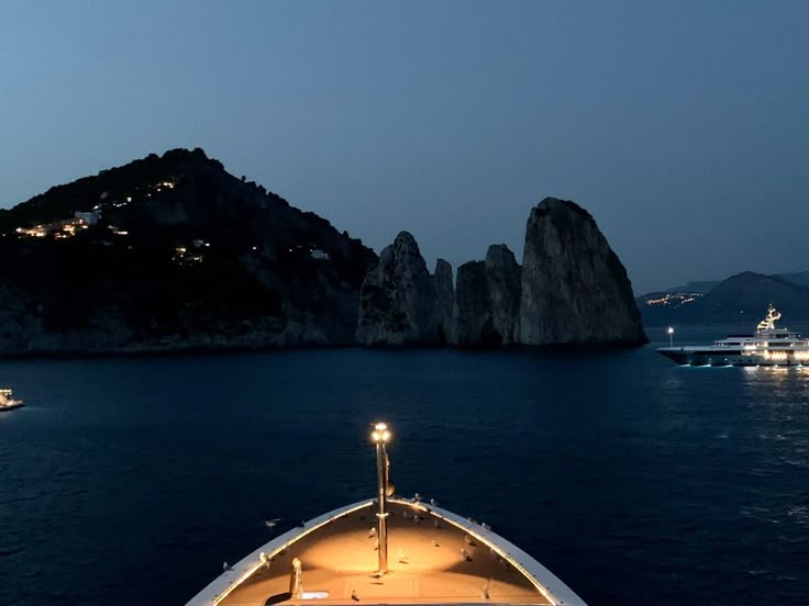 a boat is in the water at night near some mountains and boats are out on the water