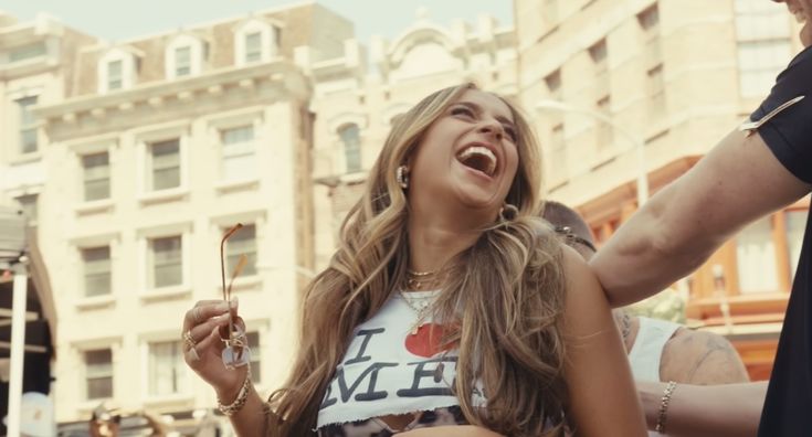 a woman laughing while standing in the middle of a crowd with other people around her