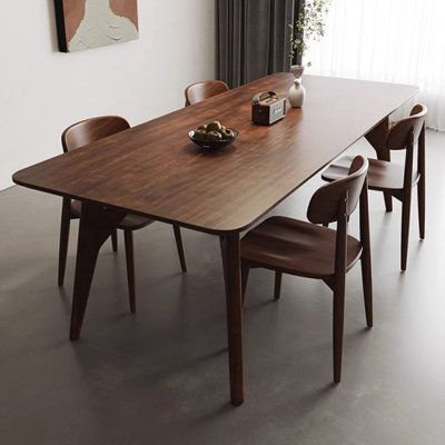 a dining room table with four chairs and a painting hanging on the wall behind it