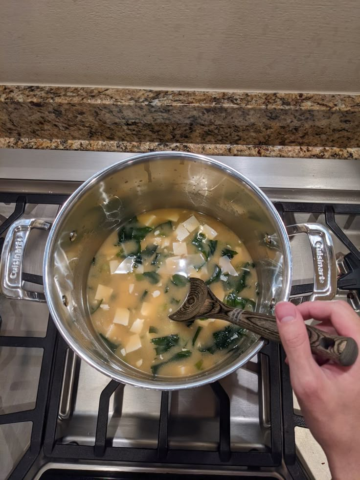 someone is cooking food on the stove with a ladle in their hand and it looks like they are going to eat something